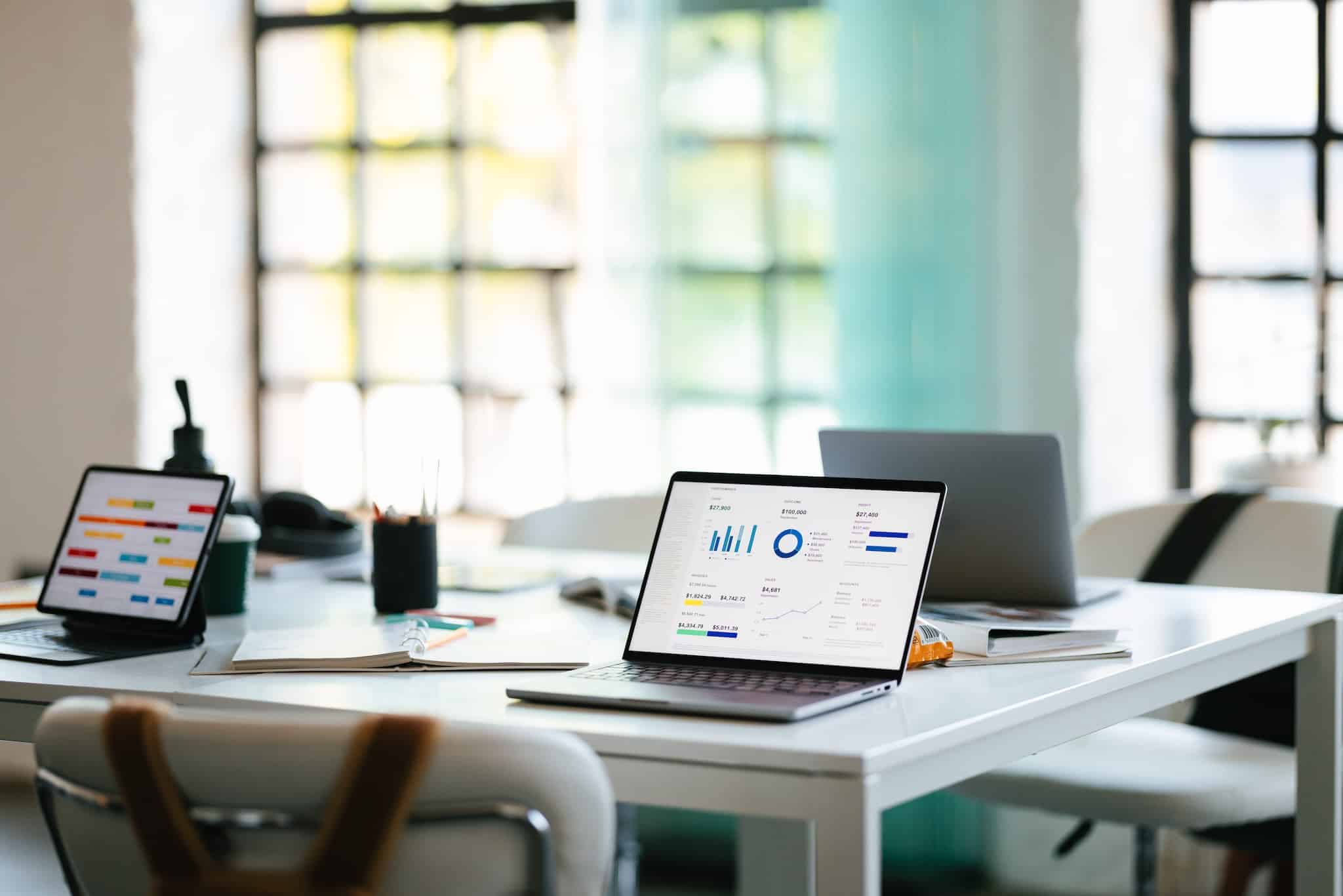 An office workspace with laptops displaying analytics, surrounded by other office items, symbolizing productivity, technology, and business collaboration.