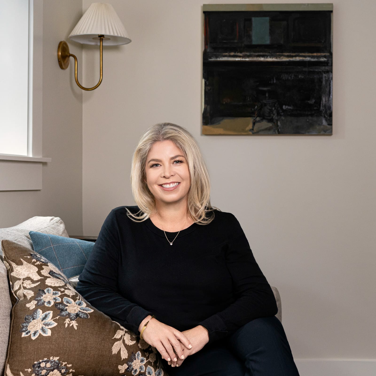 Wide Focus Founder Erin Moyer sitting on a couch with throw pillows and art behind her on the wall
