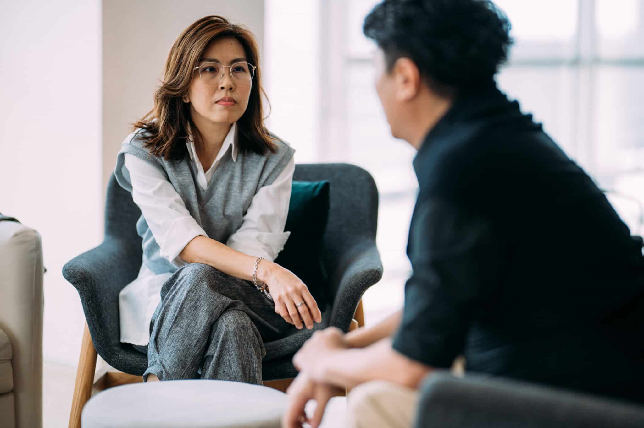 Asian woman listening while man is sharing feedback in a comfortable office setting